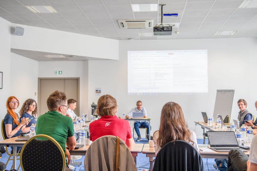 somebody presenting on a projector in a meeting room full of people