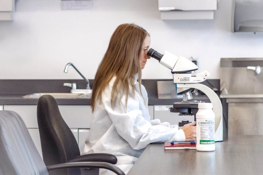 A woman in a lab coat looking in a microscope